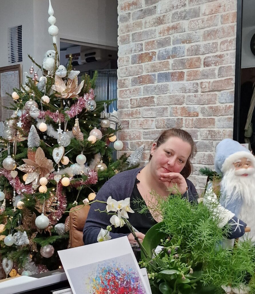 Laeticia à l’atelier, près du sapin de Noël et d’une réalisation colorée.