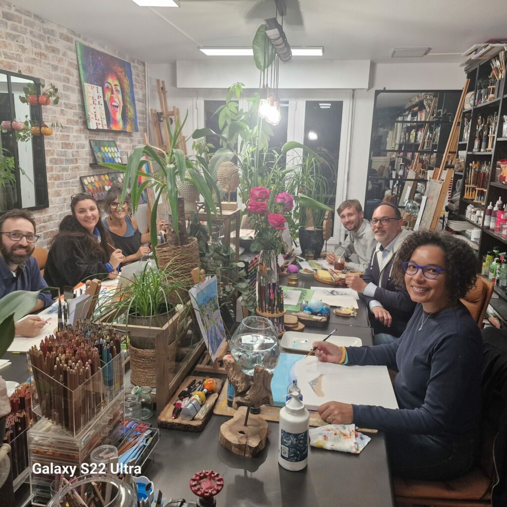 Des élèves réunis autour des tables de dessin et de peinture dans l’atelier végétalisé.